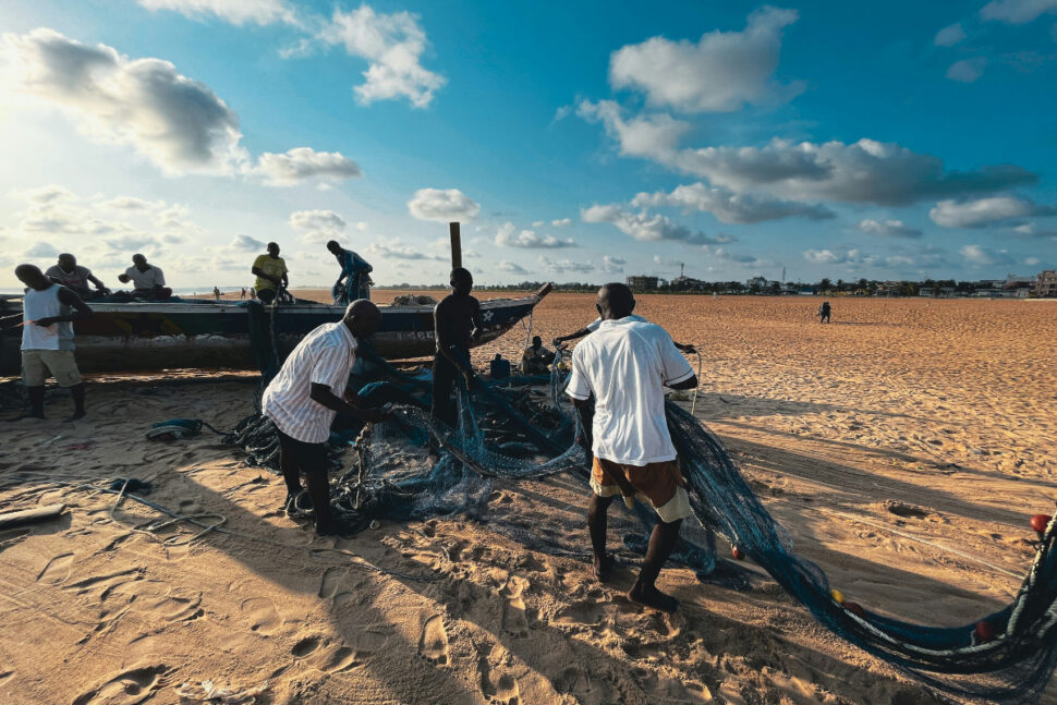 a group of men working on a boat on the beach