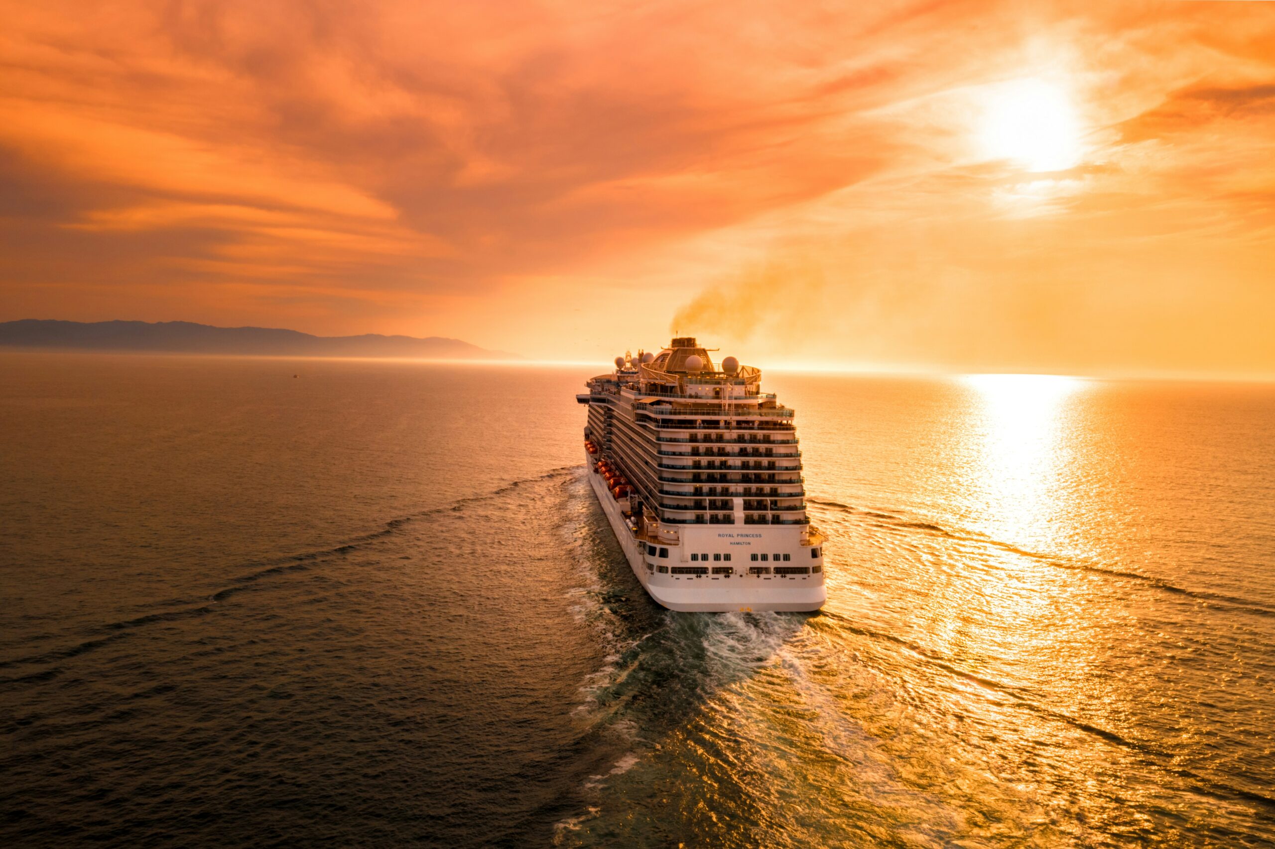 Travelers interested in Margaritaville experiences will love these offerings. 
pictured: a cruise ship cruising into the orange tinted sunset 