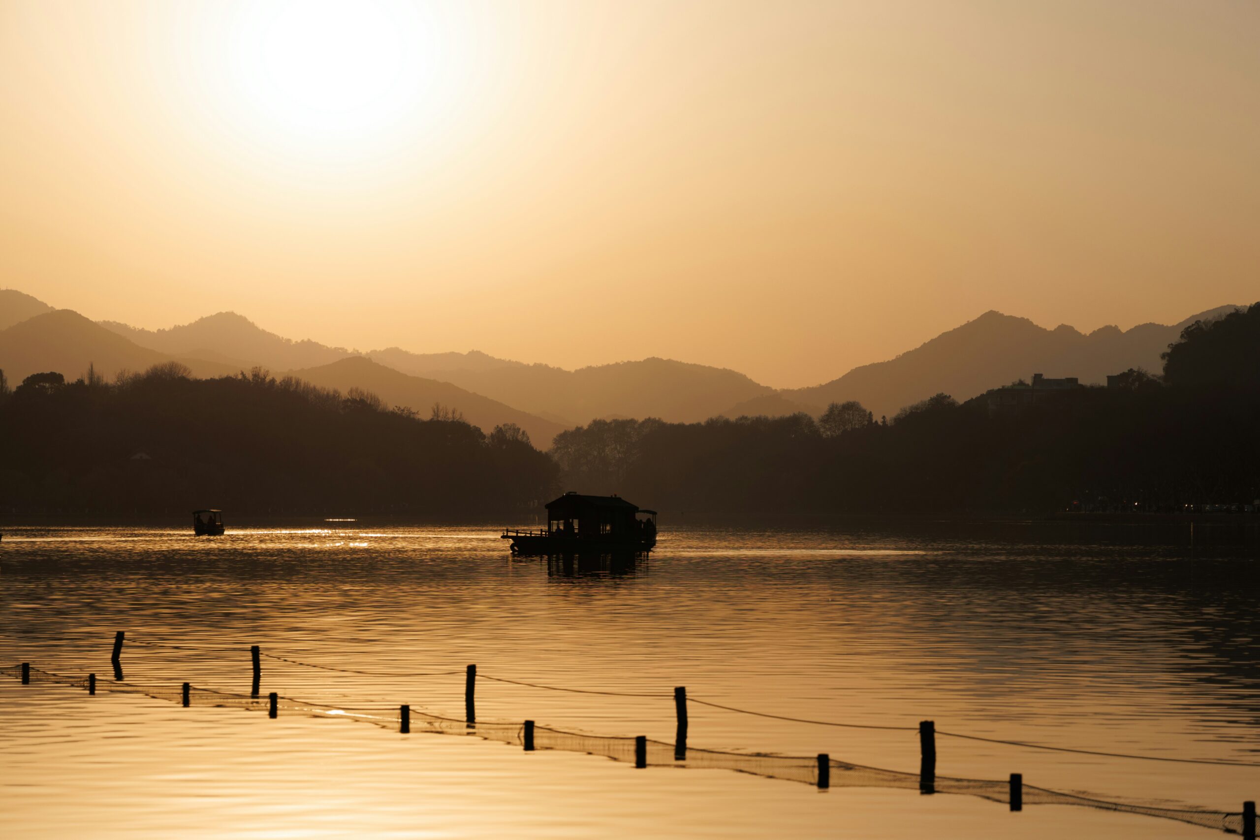 Tianducheng is a Chinese destination that travelers will find is very unique. 
pictured: a view of a river with baots in the distance during sunset in Hangzhou