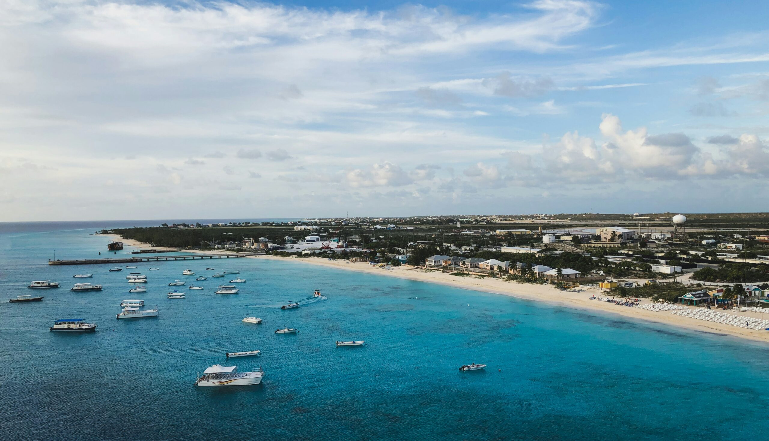Learn more about the safety level of Turks and Caicos and what travelers should expect. 
pictured: a number of boats lingering in the turquoise waters of a Turks and Caicos beach 