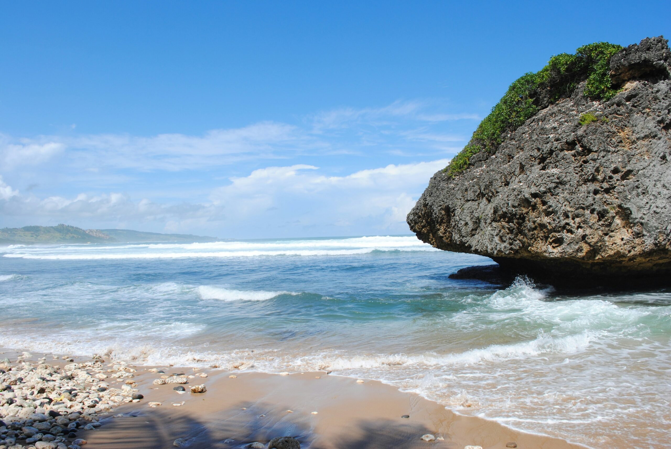these are the best travel advisories for potential travelers of Barbados.
pictured: a Barbados' beach with clear crashing waves and stunning island views 