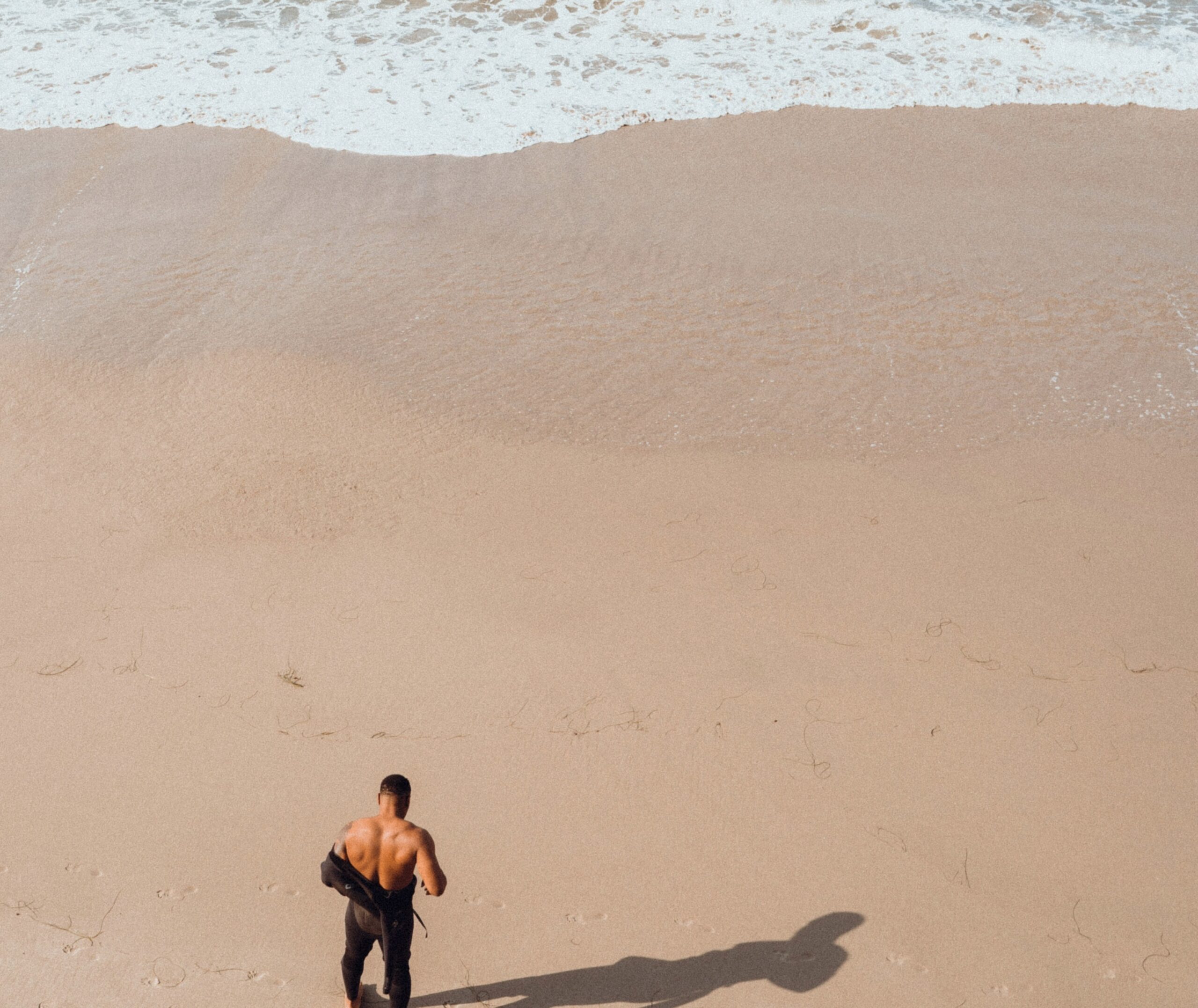 These global destinations are perfect for solo travelers. 
pictured: a man of color removing his wet suit on a sandy beach 