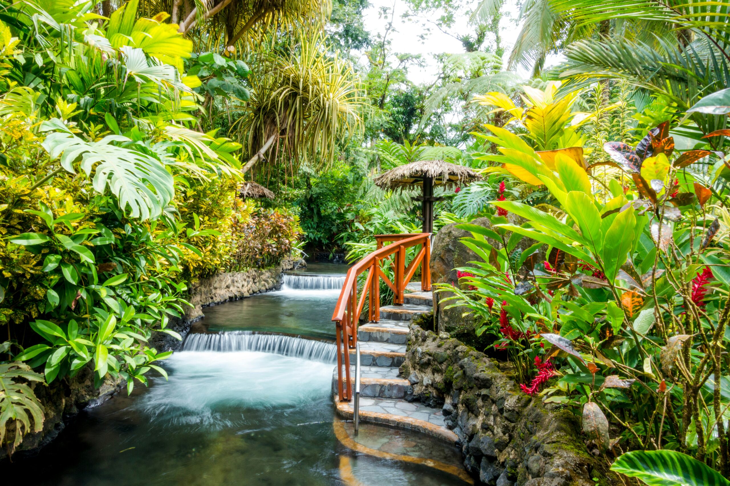 Costa Rica is a safe destination for travelers. Discover the reasons why the country is considered secure. 
pictured: a lush green rainforest with a flowing waterfall in the center in Costa Rica