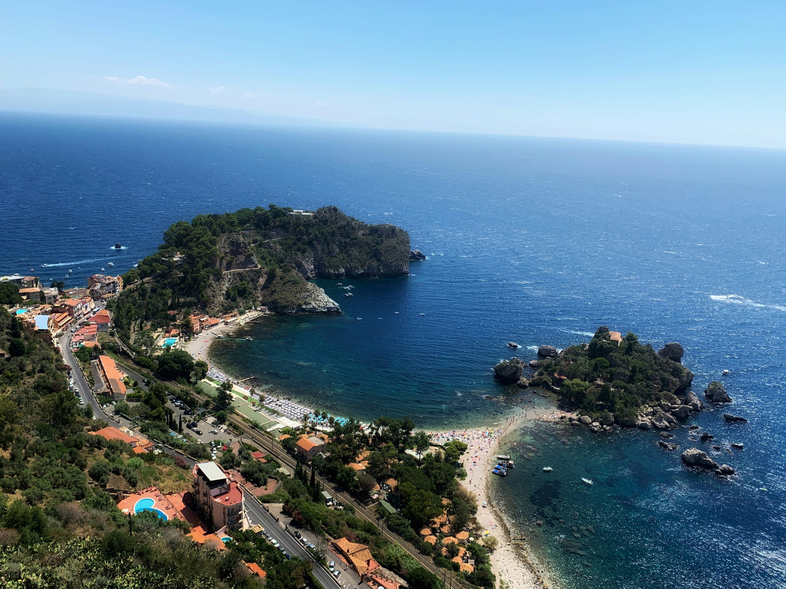 Taormina is a lesser known town of Sicily, but it is pretty accessible for tourists. 
pictured: the stunning coast of Taormina with beach homes surrounded by lush greenery