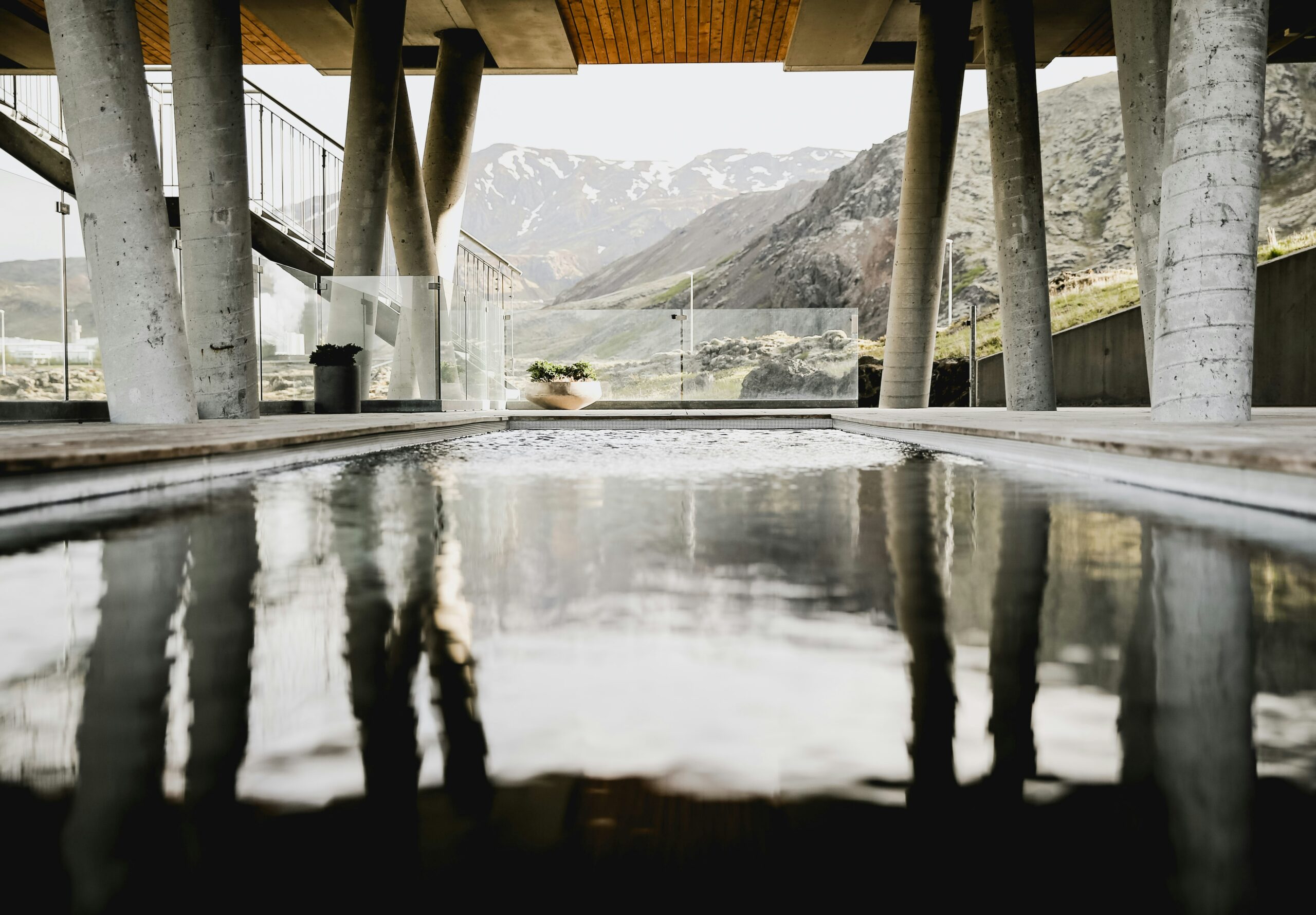 Here are reasons travelers should visit Iceland and things to consider when selecting a luxury hotel. 
Pictured: a resort with a large pool under a terrace overlooking the snowy peaks of Iceland