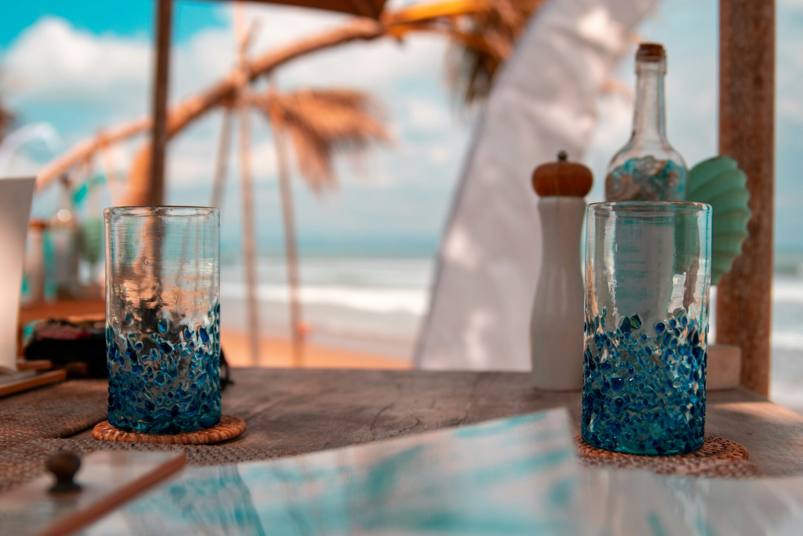 This restaurant in Guadeloupe was a primary filming location for the series “Death in Paradise”.
Pictured: a beach bar counter with decorated glasses  