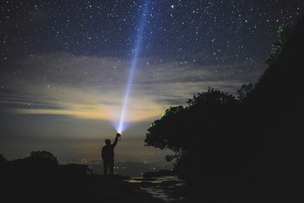 man shining flash light into night sky in Knuckles, Sri Lanka