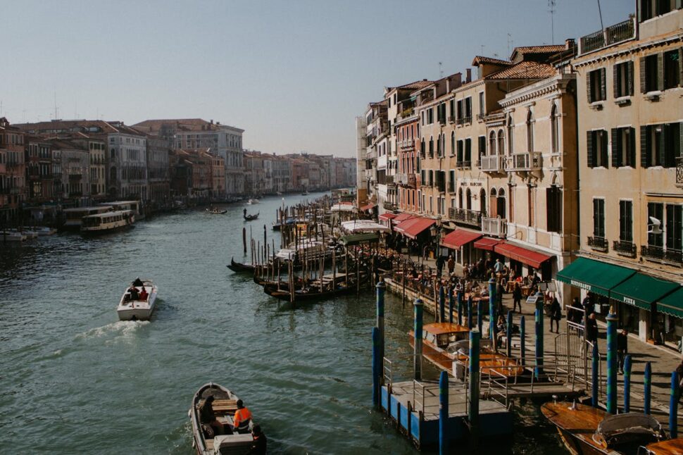 People Riding on Boat on River Near Buildings in Veneto 
