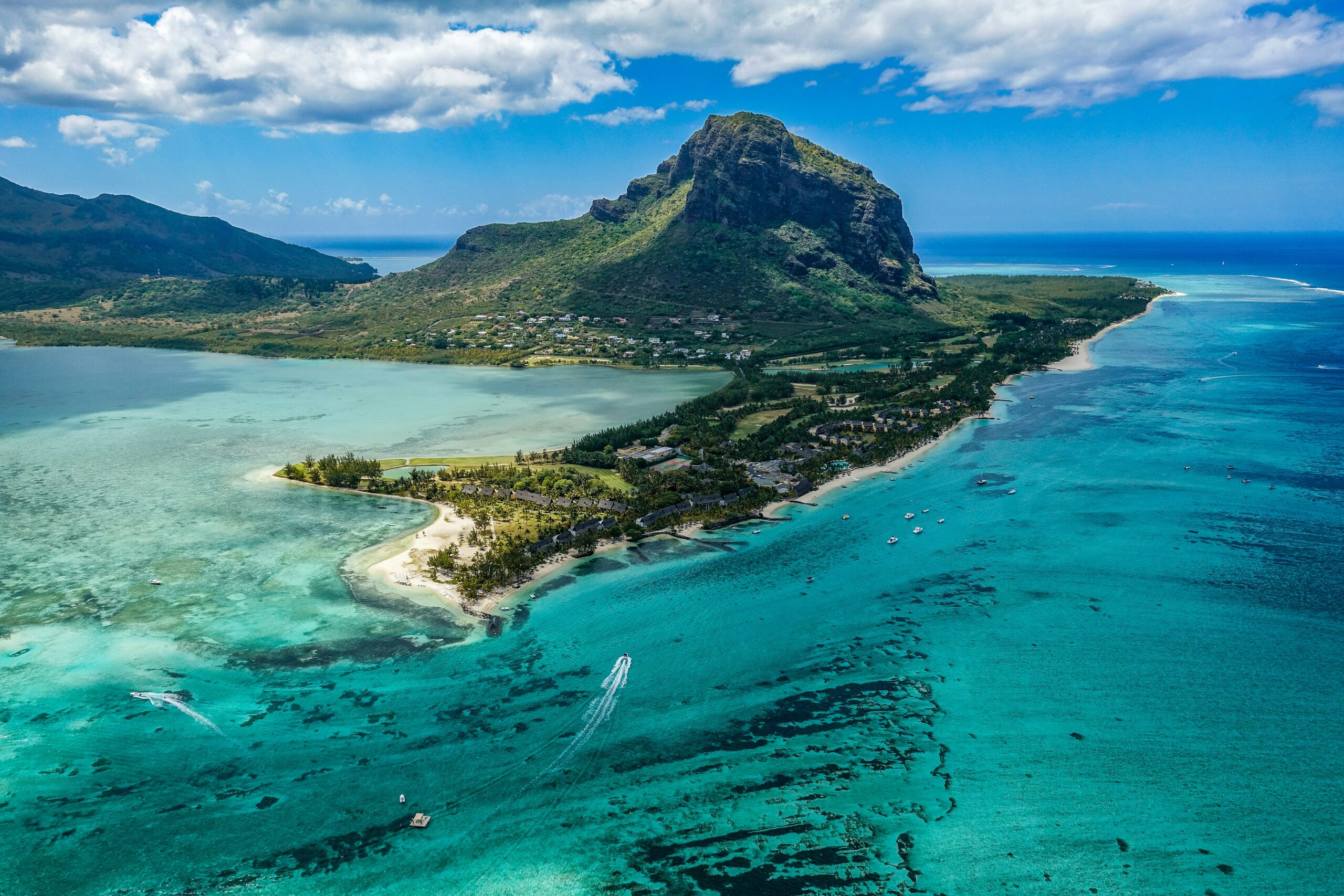 These safe islands are some of the best tropical travel spots that travelers can choose from. 
pictured: a lush green island of Mauritius with turquoise waters on a cloudy day