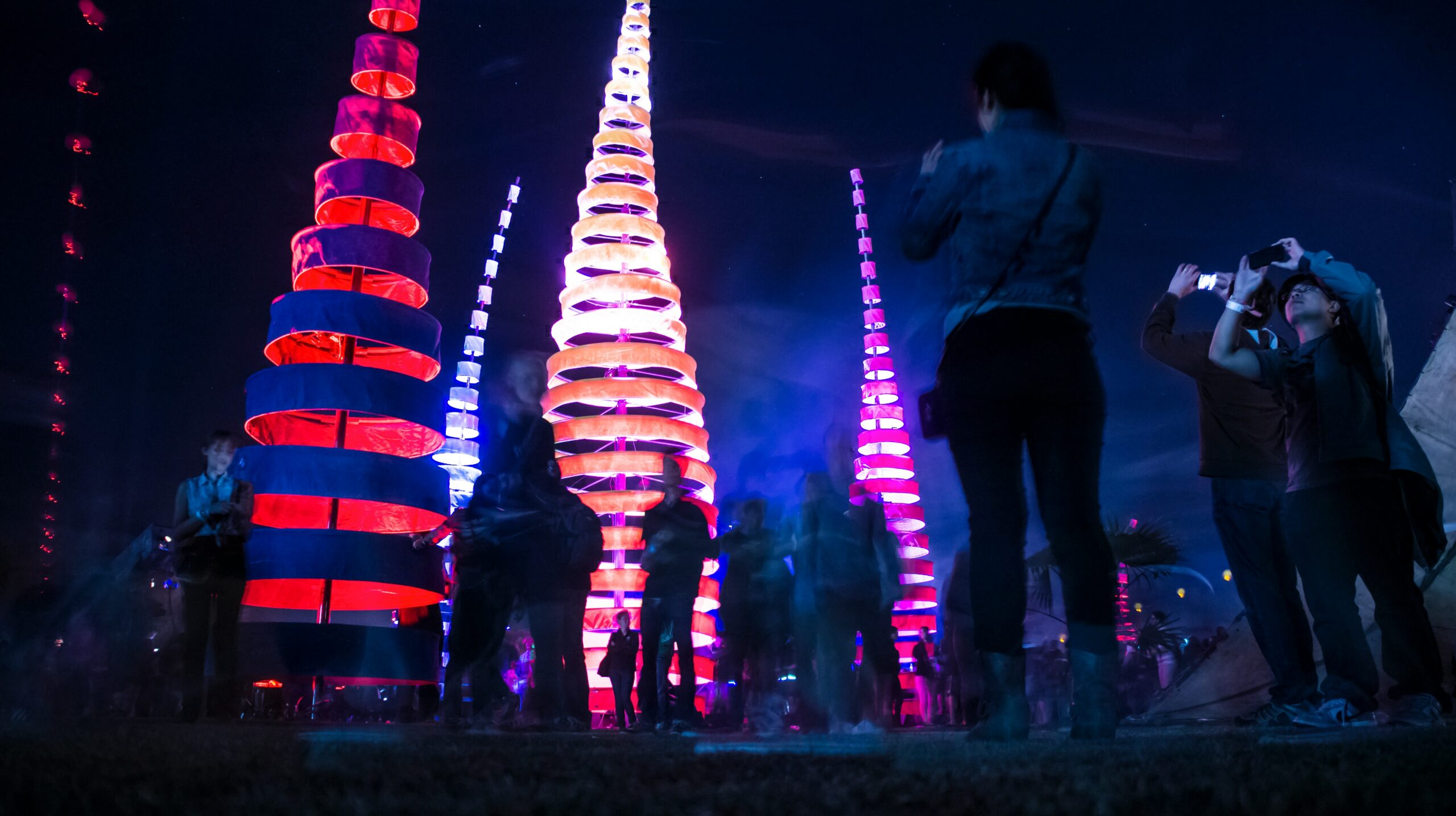 Check out some popular things to do inside of the Coachella festival.
pictured: a night at Coachella with bright glowing decor and attendees taking pictures 