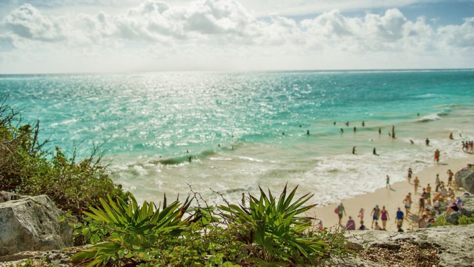 busy beach with many people in Tulum on a sunny day