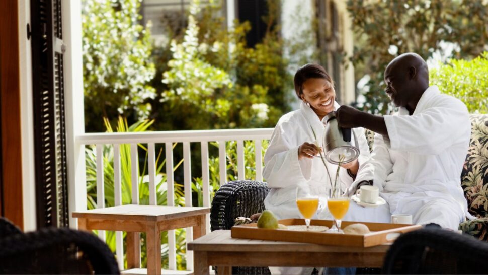 happy couple sitting on balcony of U.S. resort having breakfast in their robes