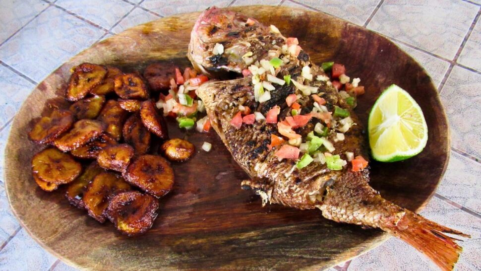 grilled fish and plaintains served on a wooden board