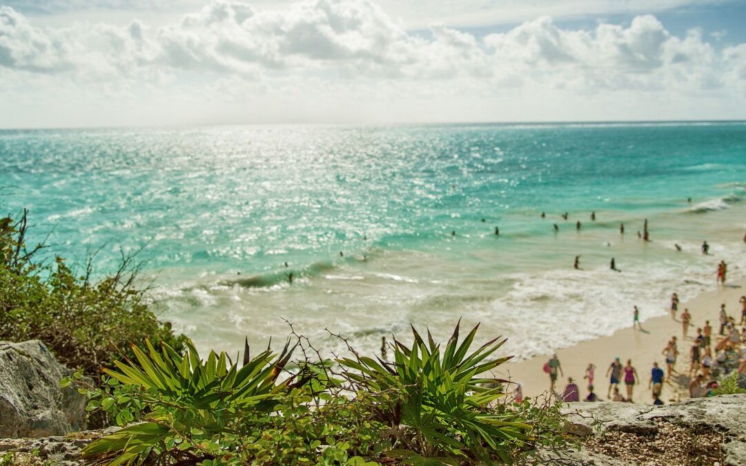 tulum vs cancun Pictured: busy beach with many people in Tulum on a sunny day