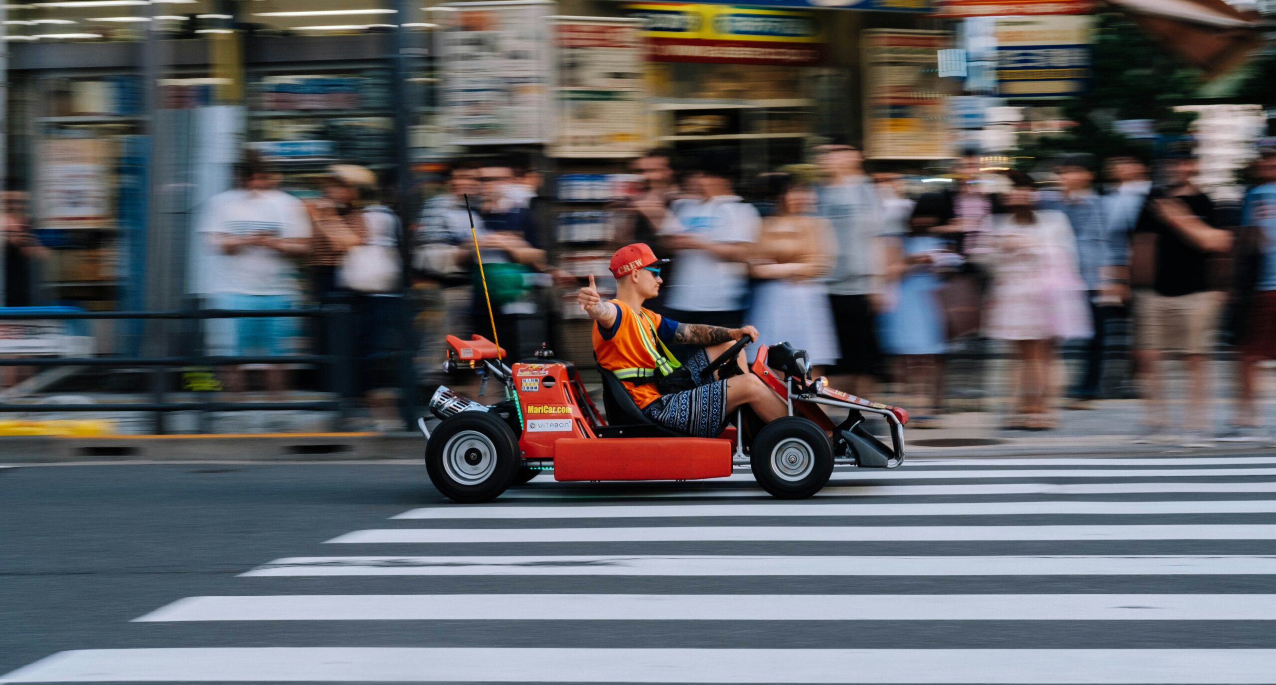 a man zooming through the streets of Akihabara on a Mario Kart