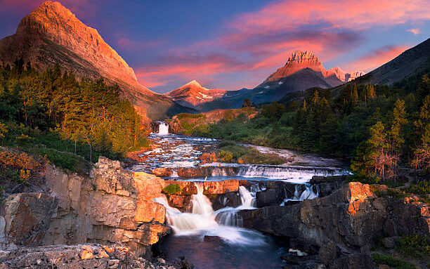 Pictured: Colorful sunrise over the rapids of Swiftcurrent Creek in Glacier National Park, Montana