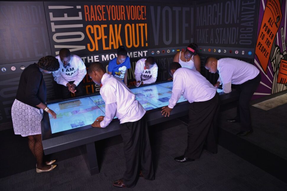 group of people standing around interactive smart table at the National Civil Rights Museum in Memphis, Tennessee